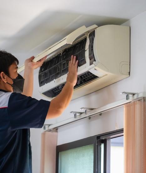 A person has a mask and doing AC maitenance